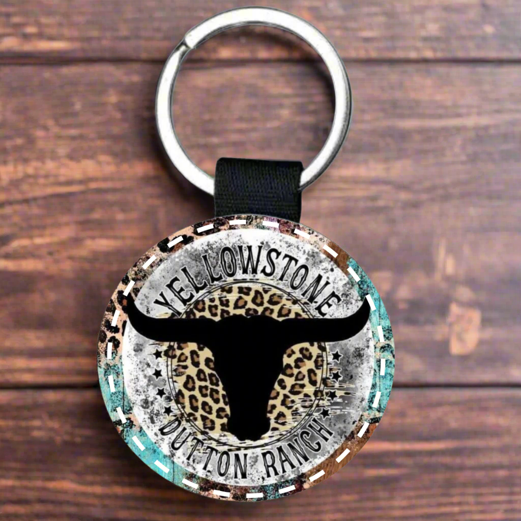 Keychain with Yellowstone Dutton Ranch design featuring a longhorn cow and leopard print on a white background..